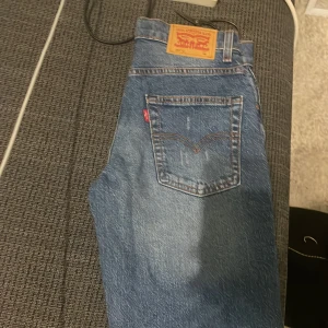 Levi's 551™Z Auth Straight blå jeans - Snygga Levi's 551™Z Auth Straight jeans i klassisk blå tvätt med raka ben och orange kontrastsömmar. Modellen har fem fickor, bälteshällor och ikonisk Levi's patch bak. Perfekt för dig som gillar en tidlös och chill look.