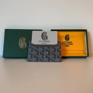 G yard korthållare i svart och grått - Exklusiv korthållare från G yard i svart och grått med ikoniskt grafiskt mönster. Slimmad design i skinn med flera fack för kort. Kommer med original ask och tygpåse, perfekt för dig som vill ha något stilrent och lyxigt i fickan.