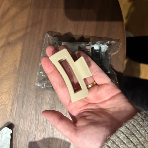 Set med hårklämmor i beige och svart - Säljer ett set med stilrena hårklämmor i matta färger, beige och svart. Klämmorna har en modern, kantig design och är tillverkade i tålig plast. Perfekta för att snabbt sätta upp håret och ge en clean look.