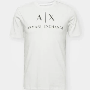 Vit t-shirt från Armani Exchange - Vit t-shirt från Armani Exchange med svart logotyptryck framtill. Klassisk rund hals och korta ärmar. Tillverkad i mjuk bomull för en skön och avslappnad passform. Perfekt för en clean och stilren look.