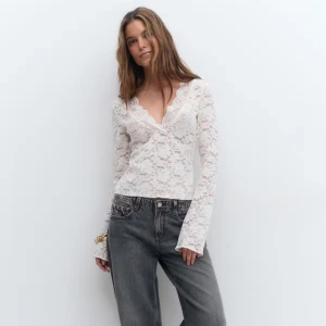 Vit spetsblus från Gina Tricot - Säljer en vit blus från Gina Tricot i storlek S. Blusen är helt i spets med omlott och v-ringad hals, samt långa ärmar. Den har en feminin och romantisk look med fina spetsdetaljer och lätt utsvängda ärmslut. Perfekt att styla med jeans eller kjol.