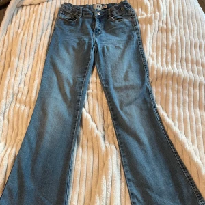 Bootcut jeans från 157, ljusblå - Snygga ljusblå bootcut jeans från 157 med klassisk femficksdesign och gul kontrastsöm. Modellen heter 90's Boot Star och har en normal passform med lite utsvängda ben. Perfekta för dig som gillar retrovibbar och bekväma jeans.