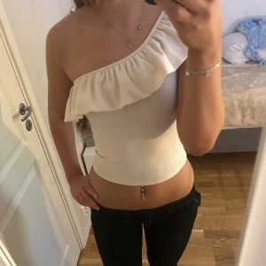 Vit topp med volang H&M - Säljer en vit, croppad one shoulder topp från H&M i storlek XS. Väldigt fin och söt topp 💞
