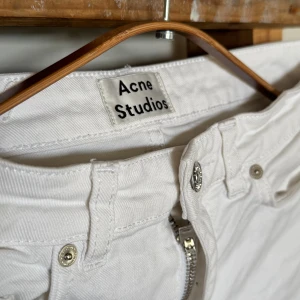 Vita jeans från Acne Studios 25/32 - Vita jeans från Acne Studios med klassisk femficksdesign och silverfärgade detaljer. Jeansen har tigth passform och är tillverkade i bomullstyg med dragkedja och knapp framtill. 