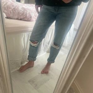 Ljusblå ripped jeans med hög midja! - Säljer ett par ljusblå jeans med hög midja och raka ben. Jeansen har snygga slitningar med hål på båda knäna och uppvikta benslut för en chill vibe. Materialet är klassisk denim och passformen är loose och straight.