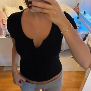 Svart topp med knappar  - Storlek M men passar även S 