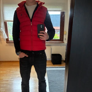 Röd dunväst från Polo Ralph Lauren - Snygg röd dunväst från Polo Ralph Lauren. Endast använd fåtal gånger och är i ett grymt skick. Jag är 178 och väger 66kg.