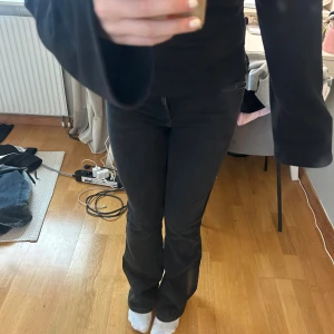 Svarta bootcut jeans med hög midja - Säljer ett par svarta jeans med bootcut som är mid waist. Jeansen har klassisk femficksdesign, dragkedja och knapp framtill. Materialet är stretchigt jeans och passformen är normal med lite utsvängda ben. Perfekt för dig som gillar en snygg siluett. Storlek 170. Knappt använda 