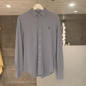 Ralph lauren skjort  - En klassisk och stilren skjorta i blå från Ralph Lauren. Har använts väldigt sparsamt och är fortfarande så gott som ny. Den är i storlek M men skulle säga att om du har S passar den lika bra. Bara att hojta till om du har några frågor! 