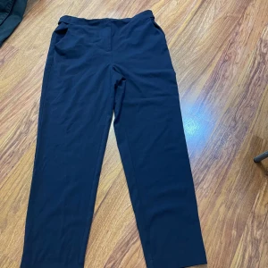 Mörkblå kostymbyxor från ONLY - Snygga mörkblå kostymbyxor från ONLY med raka ben och klassisk passform. Byxorna har fickor fram och bak, bälteshällor och stängs med knapp och dragkedja. Perfekta för en clean och stilren look.