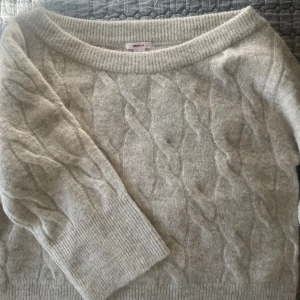 Ljusbeige kabelstickad tröja Gina Tricot - Beige stickad tröja från Gina. ”Offshoulder” liknande/ snett upptill. Kontakta för mer info och bilder. Aldrig använt.🥰