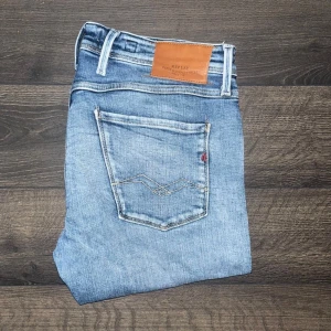 Replay Anbass jeans - Snygga ljusblå Replay Anbass jeans med klassisk femficksdesign och läderpatch bak. Jeansen har smal passform och raka ben. möjligtvis uppsydda då jag tycker 110cm är lite kort för att vara L36 så håll koll på måtten :)Midja 44cm, längd 110cm. Ifall det inte finns någon bild i annonsen där jag bär plaggen jag säljer så är det för att jag ej kan ha storleken heller passformen, så kolla måtten för storlek och googla på modellnamnet för passform 😉S2