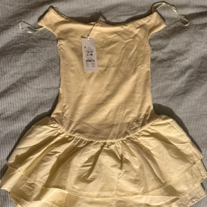 Ljusgul kort volangklänning - Supersöt ljusgul kort klänning med offshoulder-ringning och dubbla volanger i kjolen. Säljs då det blev fel storlek. Ordinarie pris:329kr