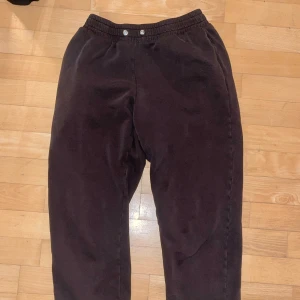 Bruna mjukisbyxor med resår - Mörkbruna mjukisbyxor med elastisk midja och muddar vid bensluten. Byxorna har en snygg passform. Perfekta för chill dagar och har fickor på sidorna. En liten söm efter ett hål på höger bak-är bild