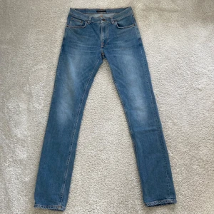 Nudie Jeans - Klassiska Nudie Jeans i ljusblå denim med stilrena blå sömmar och perfekt passform. Slim fit-modell med normal midja och lagom stretch för en bekväm men stilren look. Nypris: 1600 - 1900 kr Modell: Lean Dean Storlek W31 L34. Skick: 9/10