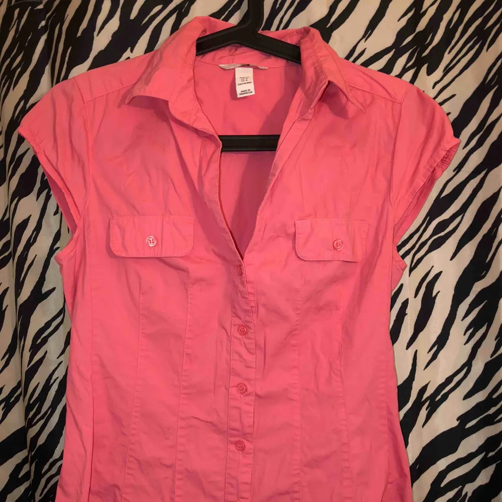 En rosa skjorta med korta ärmar. I väldigt gott skick.  Ber om ursäkt att den är skrynklig.  . Blusar.
