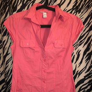 En rosa skjorta med korta ärmar. I väldigt gott skick.  Ber om ursäkt att den är skrynklig.  