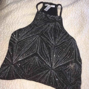  - En festtopp i färgen svart, täckt med glitter. Storlek SMALL. Använd vid ett tillfälle.  • Köparen står för frakt!