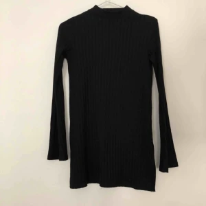  - Svart tajtare tröja med halvpolo och större ärmar. Ribbad och väldigt snygg passform. 