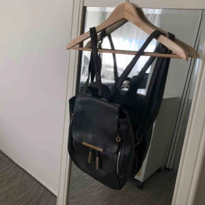  - Svart liten ryggväska med guldfärgade detaljer. Använt ett par gånger. Fortfarande i bra skikt. Kontakta för fler bilder och frågor! Frakt förekommer.