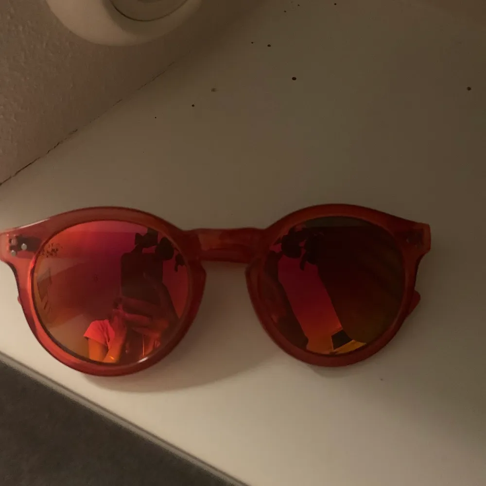 Solglasögon med röda bågar och orange/gult/rött glas. Skiftar i olika ljus. Accessoarer.