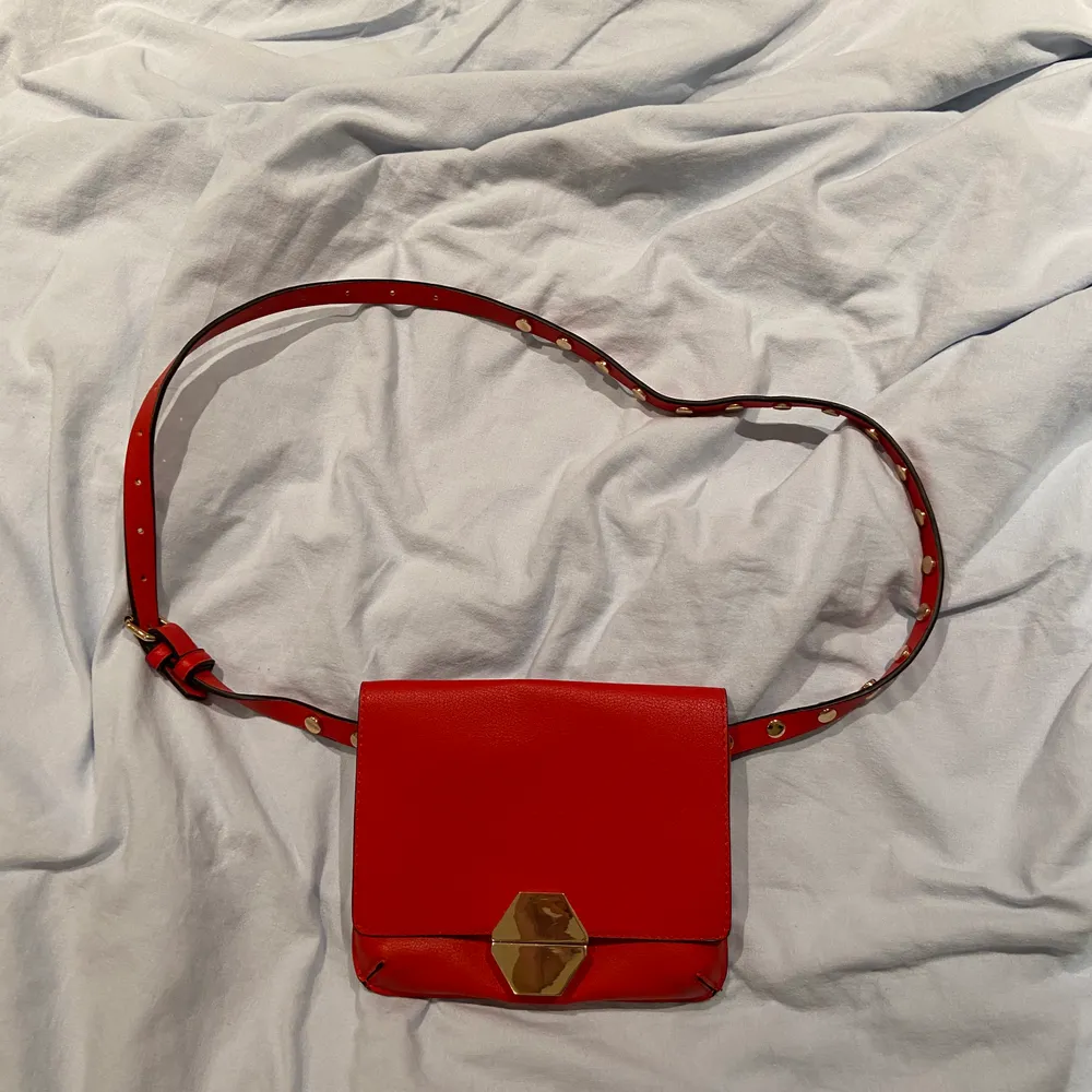 En röd väska med guldiga detaljer som funkar som både magkänsla och axelväska. Väskan är från Zara och priset är 70kr ❤️:). Accessoarer.