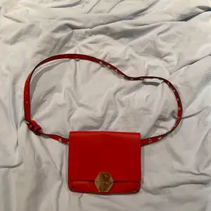 En röd väska med guldiga detaljer som funkar som både magkänsla och axelväska. Väskan är från Zara och priset är 70kr ❤️:)