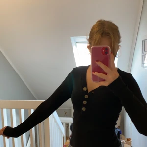 Svart räfflad tröja från Ginatricot - Svart räfflad tröja från Ginatricot med bruna knappar som går att knäppa upp. Använd ca 2 ggr så är i bra skick. 