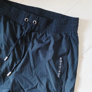 TRÄNINGSBYXOR FRÅN RÖNISCH  - Svarta ”cargo” träningsbyxor från RÖNISCH. Använda fåtal gånger. Möts på Södermalm och vid frakt står köparen för kostnad!