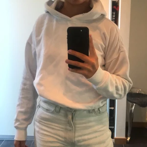 Vit hoodie - En vit hoodie från Urban classics. Har ett snöre som skickas med som kan sättas i hålen vid luvan. Fint skick men lite nopprig så därav priset. 