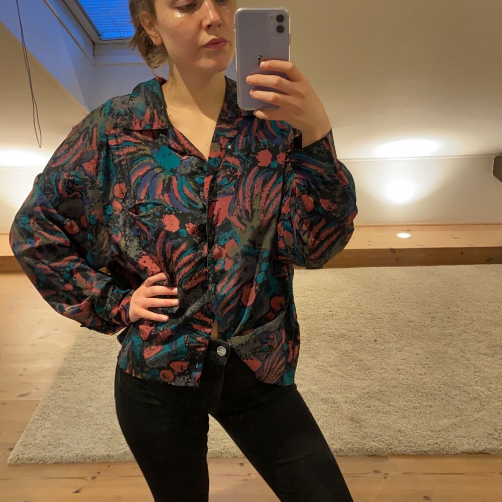 Färgglad mönstrad skjorta i 100 % polyester. Skönt silkesliknande material. Mönstrad i färgerna rosa, turkos, brun och svart. Har knappar och en krage.. Skjortor.