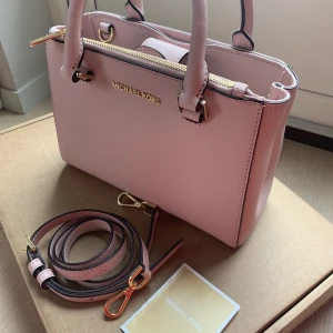 Rosa Michael kors väska  - Äkta Rosa Michael kors väska. Endast använd två gånger. Perfekt storlek. Säljer på grund av att jag inte använder den. Långt band ingår. Köparen betalar frakten.