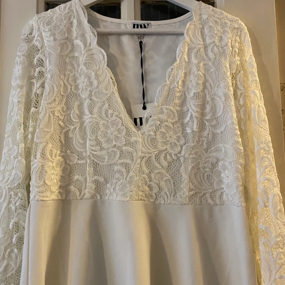 En vit klänning med spets upptill. Har aldrig använt den så prislappen är kvar. ( frakt tillkommer, om den ska skickas ) . Klänningar.