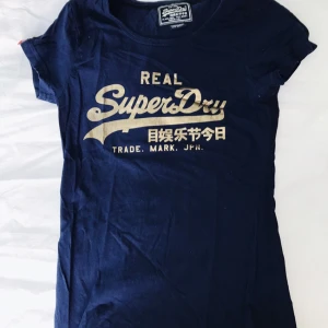 - Blå Superdry-t-shirt med guldigt tryck! Fint skick.