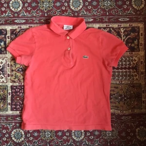  - Lacoste piké, korall-orange! Förstår inte riktigt märkningen, står 12 men passar på mig som har XS... barnstorlek/krympt i tvätt perhaps :)