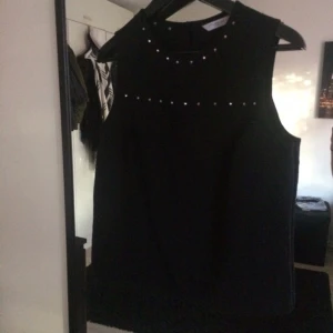  - Svart topp med silvriga detaljer. Lös passform. Passar en 36/38.