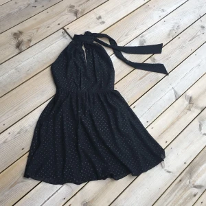  - Klänning svart med pickar som är lite glansiga, chiffong fodrad öppen rygg. Knyt runt hals. 