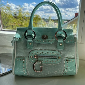 Guess väska - Guess väska i härlig ljus turkos färg. Väldigt passande nu till våren. Buda gärna :)