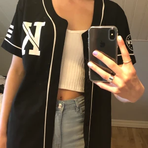 Baseball t-shirt - Svart vit baseball t-shirt i nyskick med knappar. Väldigt luftigt material. Liten i storleken då jag annars brukar ha S/M. 