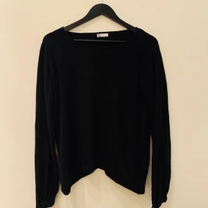 Svart tröja med detalj  - En super fin tröja med gulliga detaljer vid ärmens slut. Aldrig använd. Storlek L och är köpt på Cubus. 