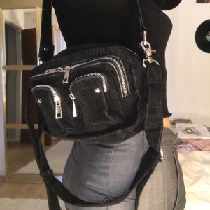 Nunoo väska - Svart Manchester Nunoo väska. Många justerbara band och fack med mycket utrymme! Köparen står för frakten! Kontakta för mer info