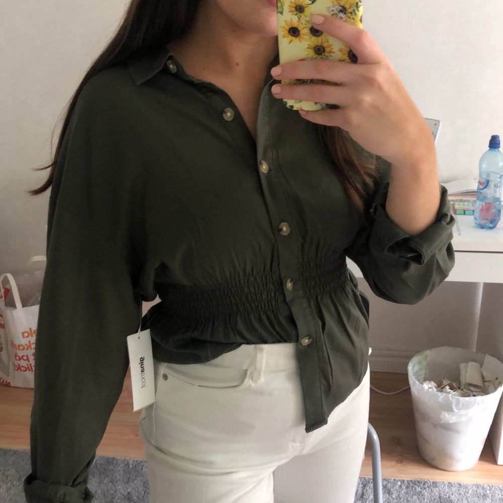 En militärgrön skjorta från Gina Tricot med smock detalj i midjan, för att skapa en fin figur. Strl 36. Helt oanvänd med prislapp kvar. Köpt för 350kr men säljer för 250kr + frakt. Önskas fler bilder är det bara att hojta till🌸. Skjortor.