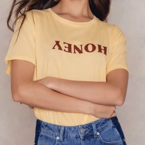 •Tshirt från Na-Kd• - superfin tshirt från Na-Kd, gul med mörkbrunt tryck, använd men i mycket bra skick! Frakt tillkommer✨