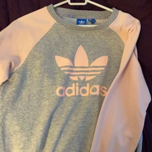 Adidas tröja storlek 38  - Rosa grå äkta adidas tröja, haft den 2 år men använt max 2 gånger, storlek 38 (M) passar som small också. Bra i skick. Ordinariepris 599kr.