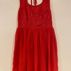 Röd klänning i S - Röd klänning med fina spetsdetaljer och djup rygg. Storlek small 