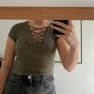 Grön topp med snörning - Mörkgrön topp från Bik Bok med snörning över bröstet som går att anpassa. Superfint skick, passar XS/S. Köparen står för fraktkostnad och betalar via Swish.