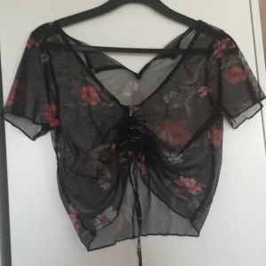 Svart mesh topp stl s  - Mesh topp med blommor. Går att knyta upp och ha som normal topp (se bild 1 och 2) 