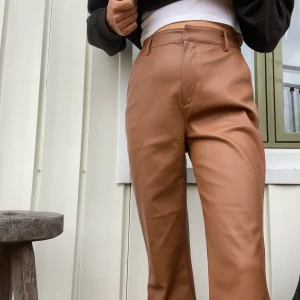 Faux skinnbyxor i brun med bootcut  - Byxorna är använda 1 gång och tvättade 1 gång. Har 2 framfickor, dragkedja samt spänne och knapp vid midjan. Superskönt material inuti som inte fastnar mot huden. Den är stor i storleken! (Sönder vid lappen pga att jag tejpat där). 