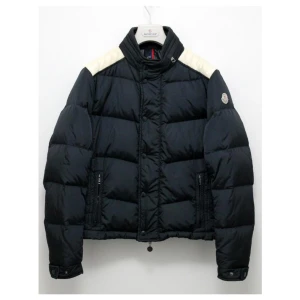 Moncler Austin - Storlek 5, använd sparsamt, finns dock lite smuts på dem vita delarna (axlarna), inget man märker av jätte mycket. Utöver det så är skicket väldigt bra och är därav en 7.5/10. Nypris låg på 8000kr. Passar till både dam och herr, tänk dock på att den är mindre i storleken. 5 är oftast XL men på den här modellen är den mer som en L.