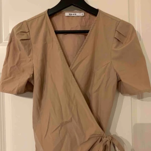  - Fin fest-topp från NA-KD i den perfekta beiga färgen. Man knyter den omlott så man kan justera urringningen som man vill! 